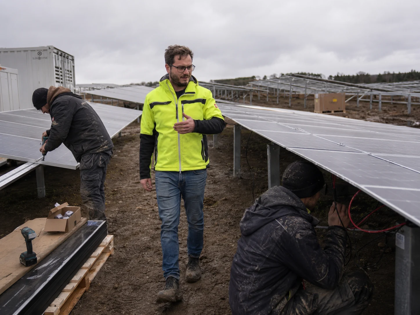 Christopher Wilmes und weitere Personen zwischen Photovoltaikreihen im Aufbau